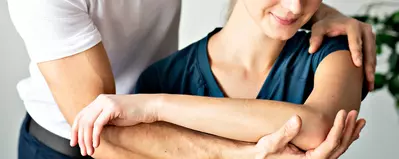 man helping woman stretch shoulders