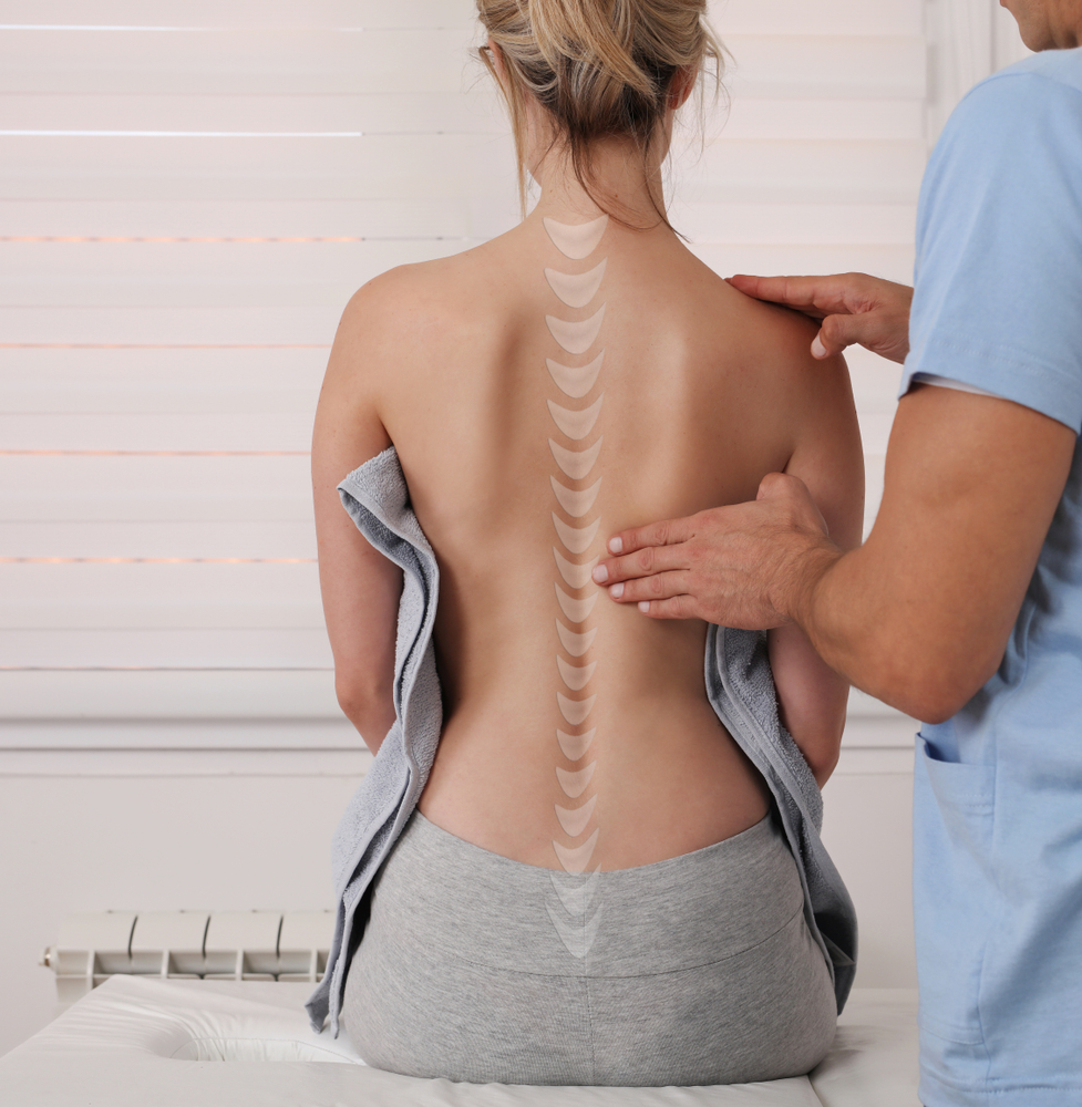 pressing on woman's back with diagram of her spine