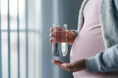 pregnant woman holding glass of water