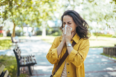 woman sneezing in park