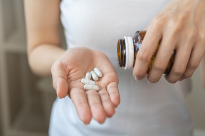 woman pouring supplements into hand