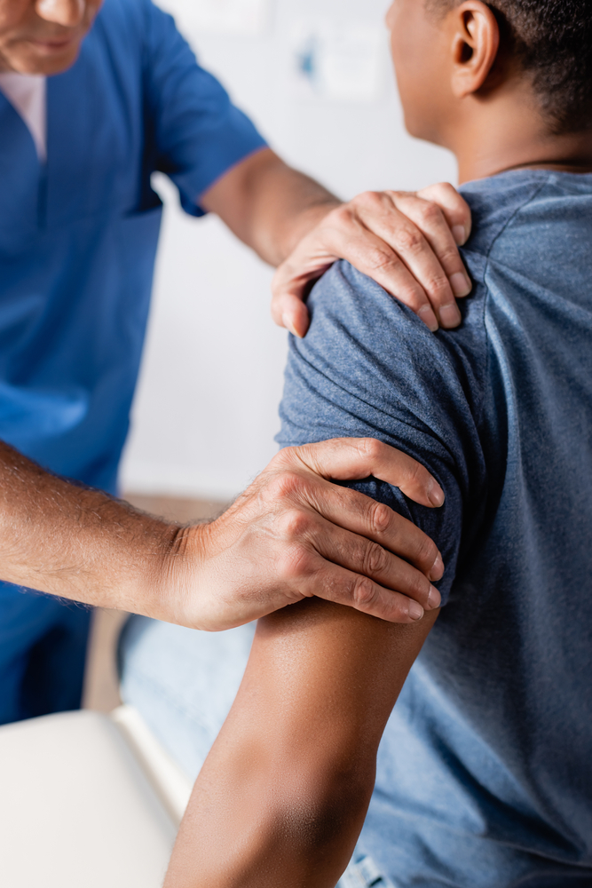 chiropractor with hands on patient's shoulder