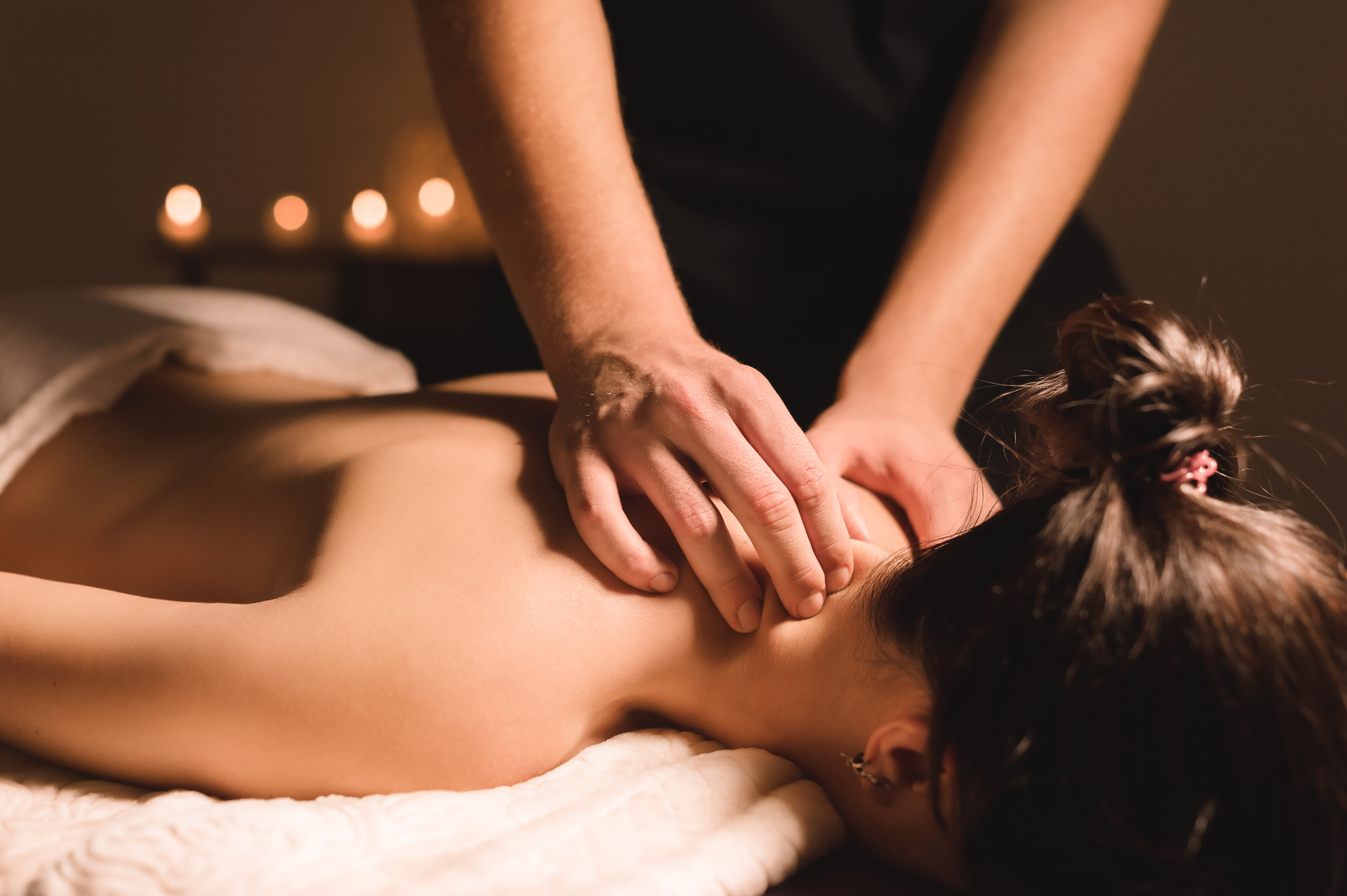 hands massaging back of man's shoulder